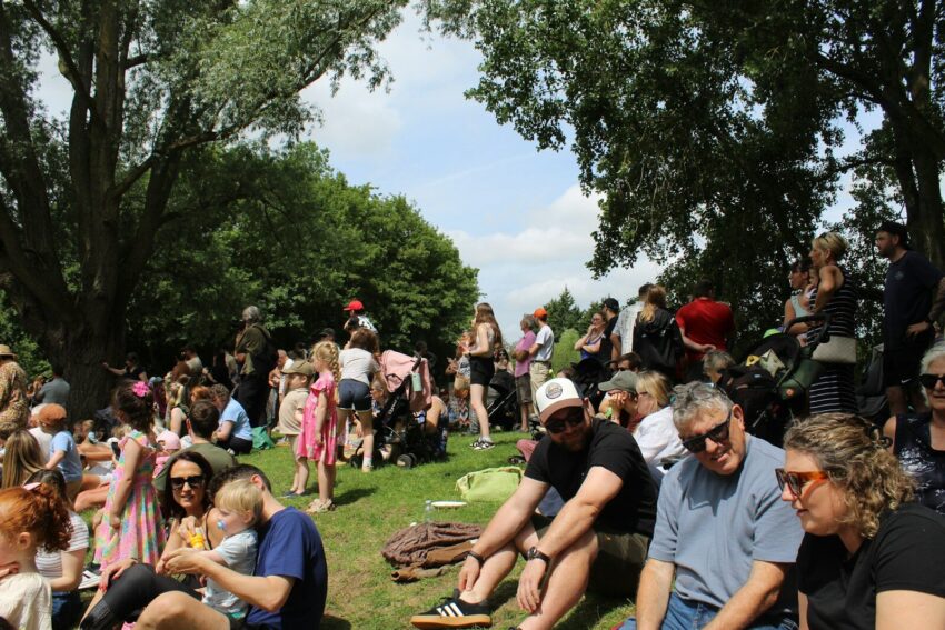 Large group of people relaxing outdoors on a green hill.